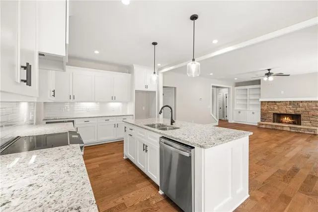 a large kitchen with kitchen island a sink stainless steel appliances and a fireplace