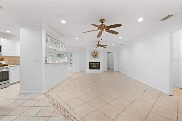 a view of an empty room with a window and kitchen view