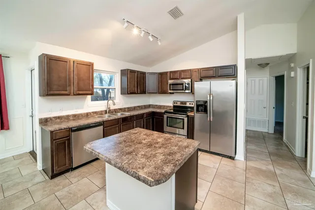 a kitchen with stainless steel appliances granite countertop a sink stove refrigerator and cabinets