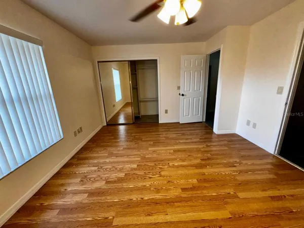 a view of an empty room with closet and wooden floor