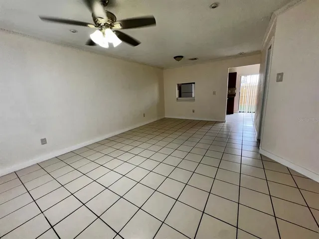 a view of an empty room and chandelier fan
