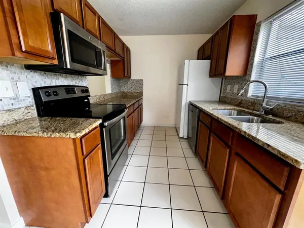 a kitchen with stainless steel appliances granite countertop a stove a sink and a microwave