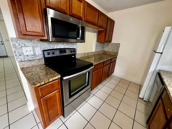 a kitchen with granite countertop a stove top oven a sink a counter space and cabinets
