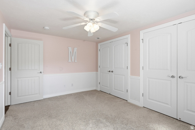2420 West Old Hwy Road Morgan, UT 84050 - Photo 38 of 54 Unfurnished bedroom featuring a wainscoted wall, multiple closets, light colored carpet, and ceiling fan