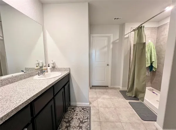 a bathroom with a granite countertop sink a mirror and a shower