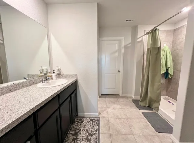 a bathroom with a granite countertop sink a mirror and a shower