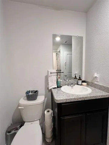 a bathroom with a granite countertop toilet sink and mirror