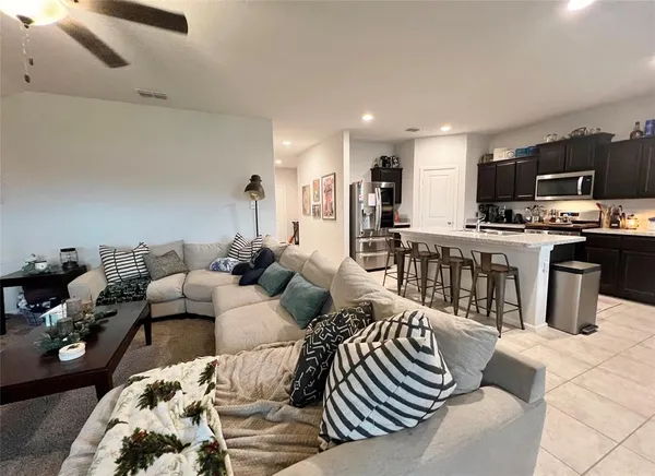 a living room with furniture a flat screen tv and kitchen view
