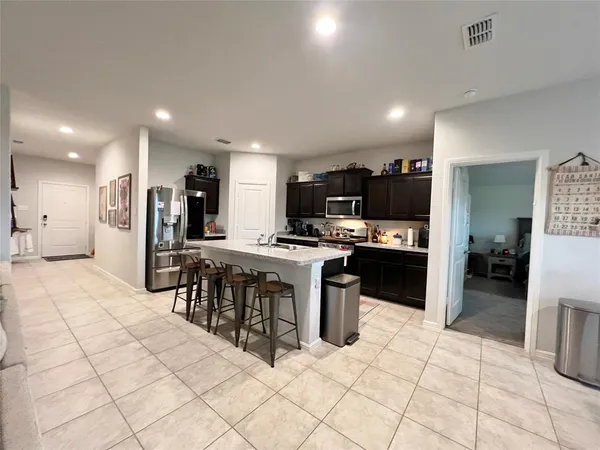 a kitchen with stainless steel appliances kitchen island granite countertop a refrigerator and a sink