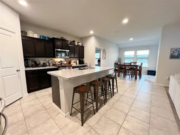 a kitchen with stainless steel appliances granite countertop a stove top oven a sink a counter top space cabinets and a view of living room