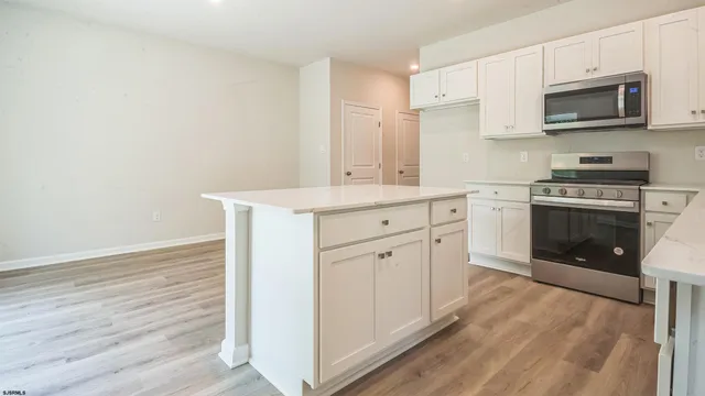 a kitchen with stainless steel appliances granite countertop a stove top oven a sink and white cabinets