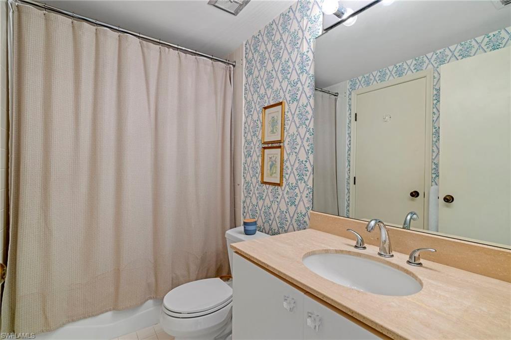 4451 Gulf Shore Boulevard North, Unit 2002 Naples, FL 34103 - Photo 18 of 42 a bathroom with a granite countertop sink toilet and a mirror