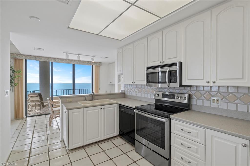 4451 Gulf Shore Boulevard North, Unit 2002 Naples, FL 34103 - Photo 8 of 42 a kitchen with stainless steel appliances granite countertop a stove a sink and a refrigerator