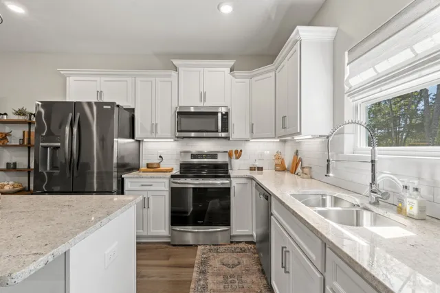 a kitchen with stainless steel appliances granite countertop a sink stove microwave and refrigerator
