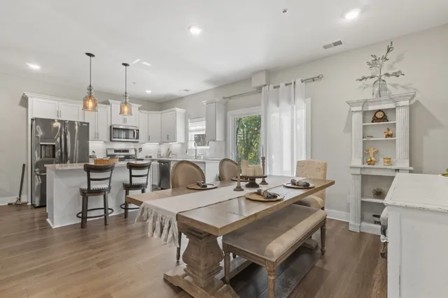 a kitchen with stainless steel appliances a dining table chairs stove refrigerator and cabinets