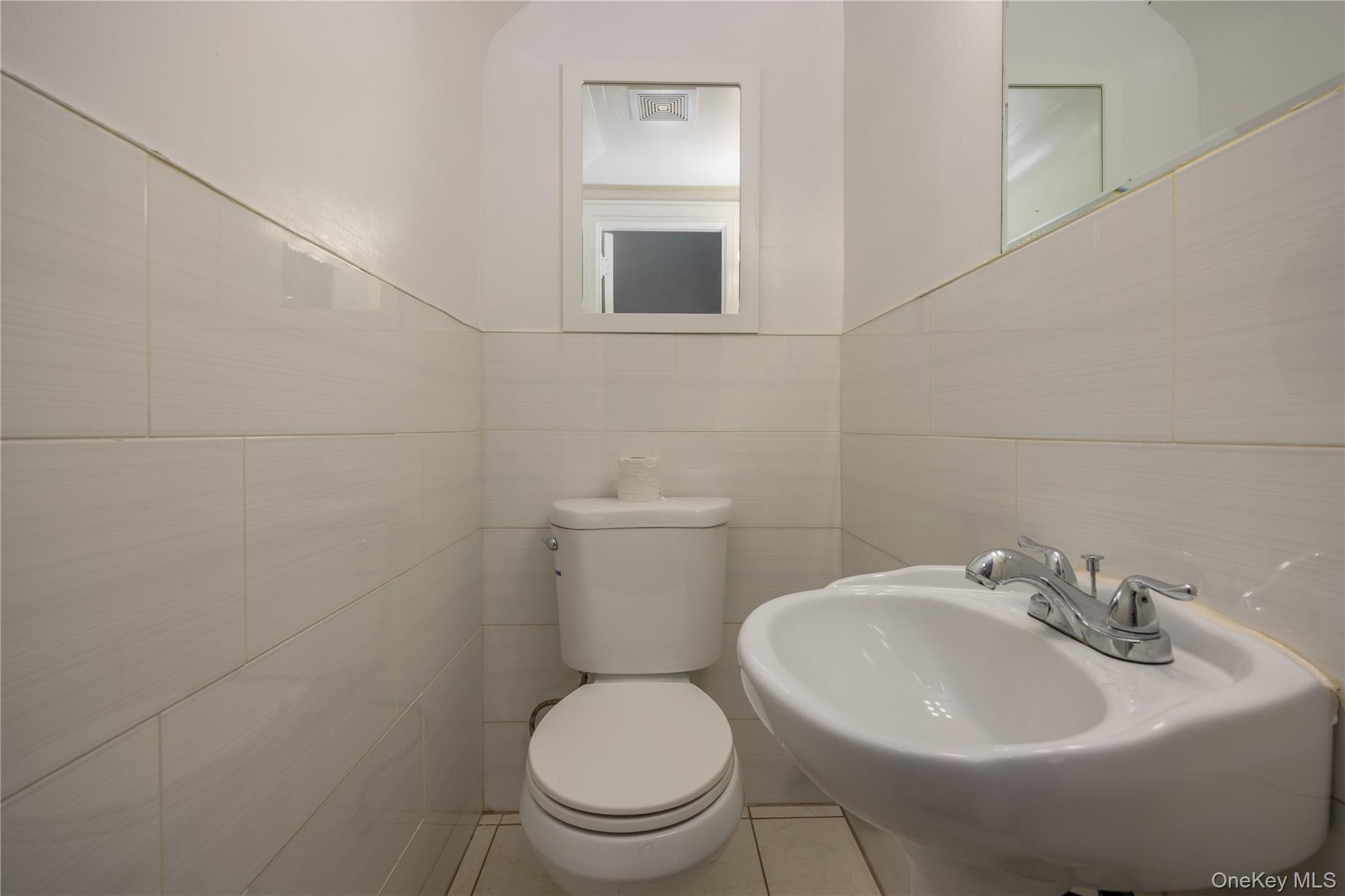 179-65 Selover Road Queens, NY 11434 - Photo 15 of 33 First floor half Bathroom featuring a wall-mounted sink, a toilet, and ceramic wall tiling