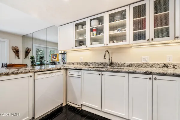 a white kitchen with granite countertop a sink and white cabinets