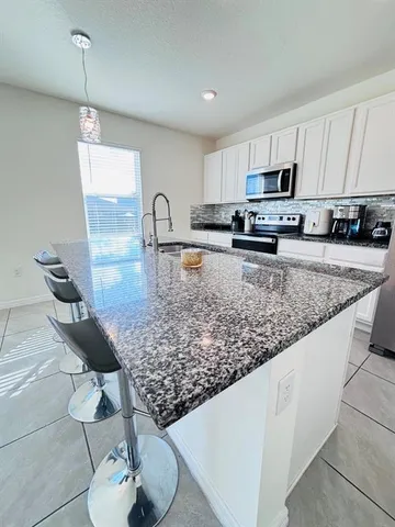 a kitchen with stainless steel appliances granite countertop a sink a stove top oven a counter space and cabinets