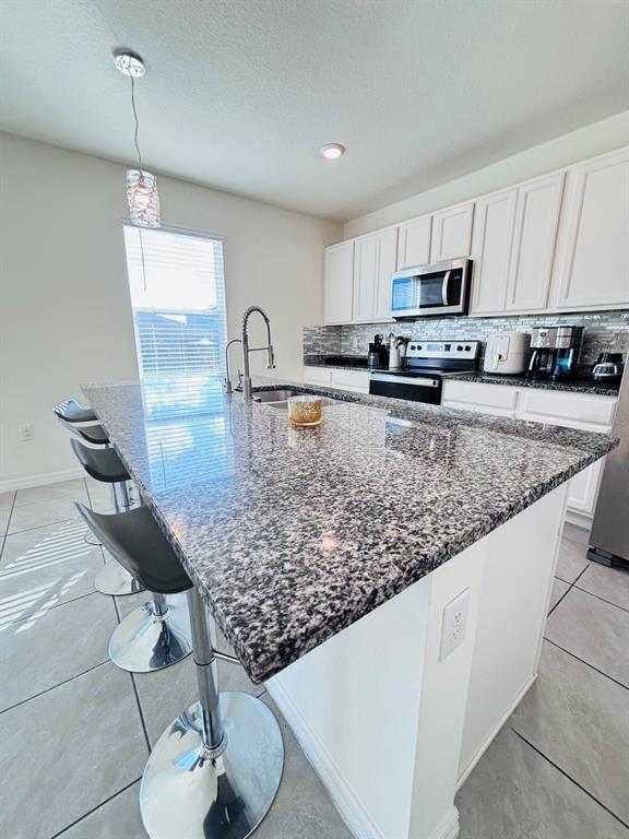5185 Barombi Bend St. Cloud, FL 34772 - Photo 12 of 47 a kitchen with stainless steel appliances granite countertop a sink a stove top oven a counter space and cabinets