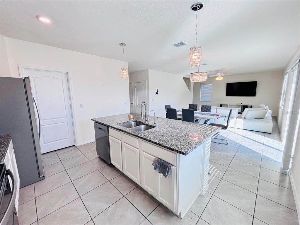 5185 Barombi Bend St. Cloud, FL 34772 - Photo 14 of 47 a kitchen with stainless steel appliances granite countertop a sink and a refrigerator