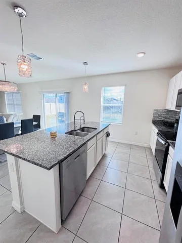 a kitchen with granite countertop a sink a counter top space cabinets and stainless steel appliances