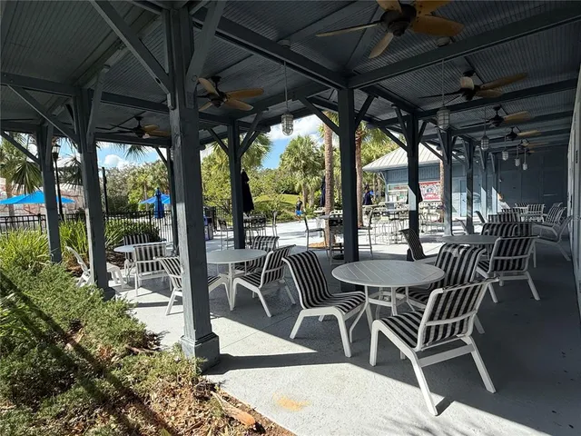 a view of a patio with table and chairs potted plants and floor to ceiling window