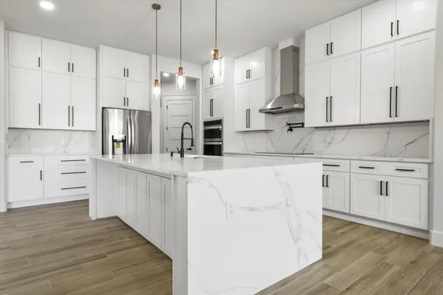 a kitchen with stainless steel appliances white cabinets and wooden floors