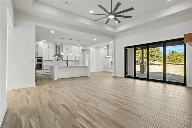 a view of an empty room with window and wooden floor