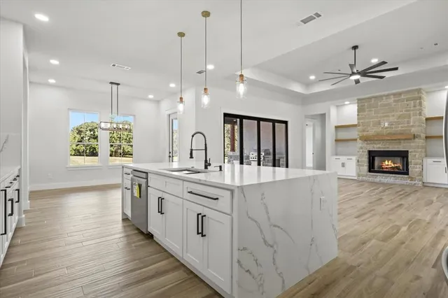 a large kitchen with granite countertop a stove oven a sink dishwasher and a fireplace with wooden floor