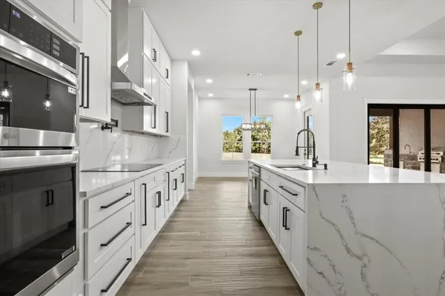 a large kitchen with granite countertop lots of counter space and wooden floor