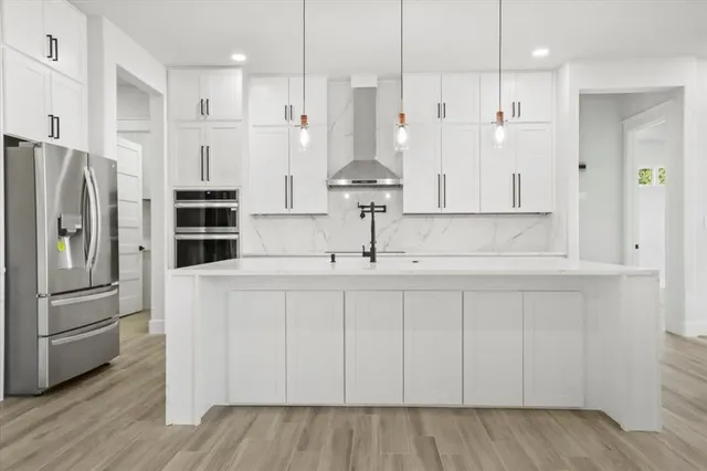 a kitchen with stainless steel appliances granite countertop a refrigerator a sink and white cabinets