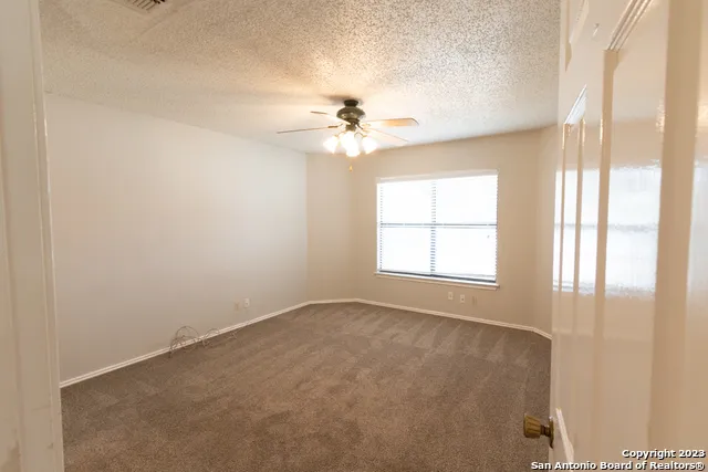 an empty room with windows and chandelier fan