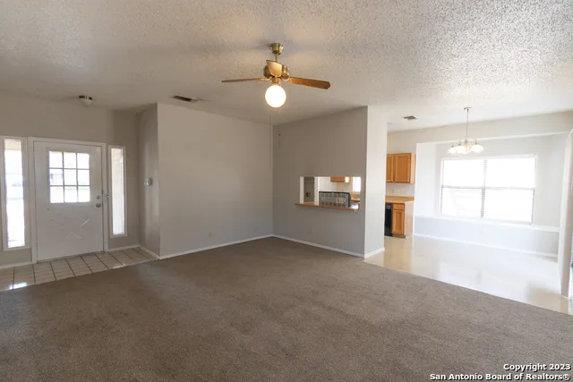an empty room with windows and ceiling fan
