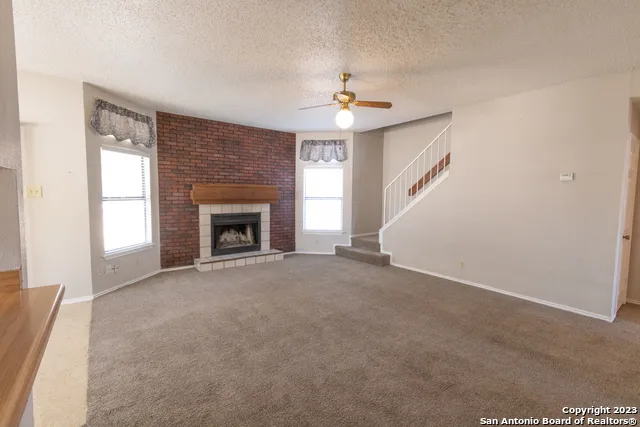 an empty room with windows and fireplace