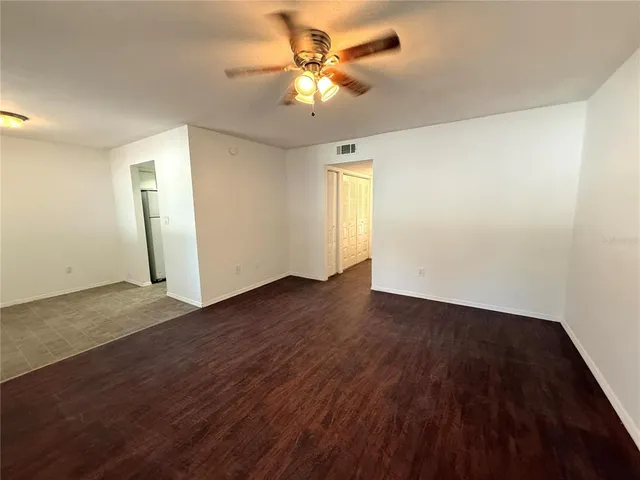 an empty room with wooden floor and a ceiling fan