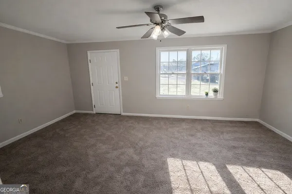 a view of a big room with windows and chandelier fan