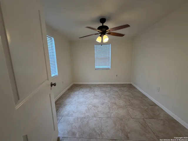 an empty room with windows and a chandelier fan