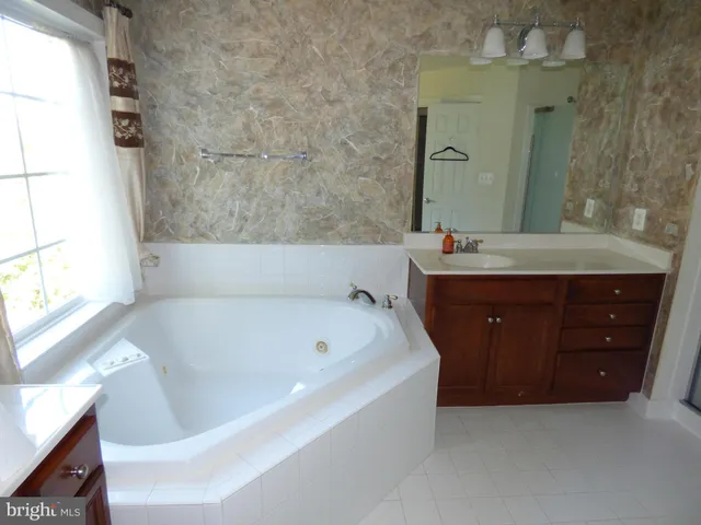 a spacious bathroom with a tub sink and mirror