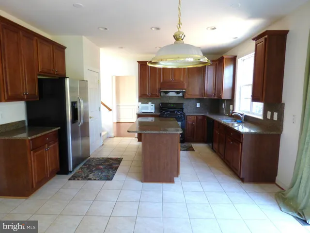 a kitchen with stainless steel appliances granite countertop a stove top oven a sink dishwasher a refrigerator and a oven