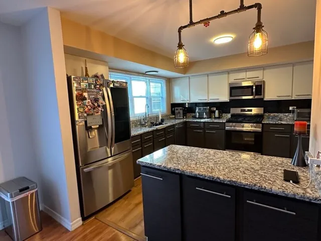 a kitchen with stainless steel appliances granite countertop a sink a stove and refrigerator