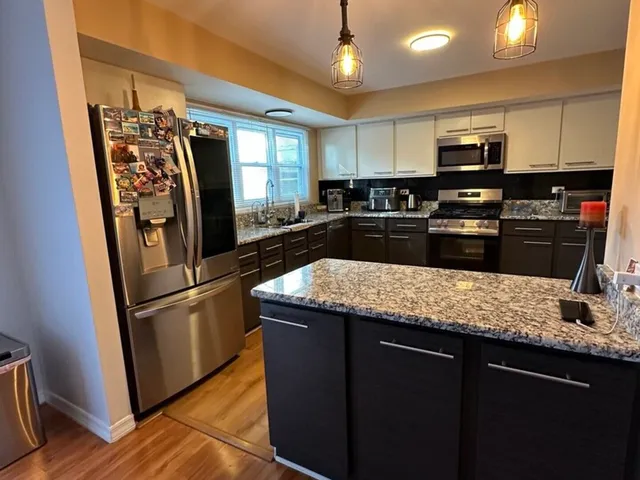 a kitchen with stainless steel appliances granite countertop a refrigerator a stove a sink and a microwave