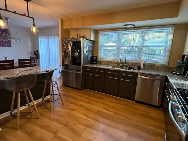 a kitchen with stainless steel appliances granite countertop a table chairs sink and cabinets