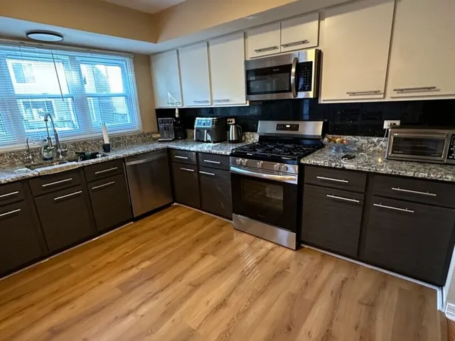 a kitchen with stainless steel appliances granite countertop a stove a sink dishwasher and a microwave oven with cabinets