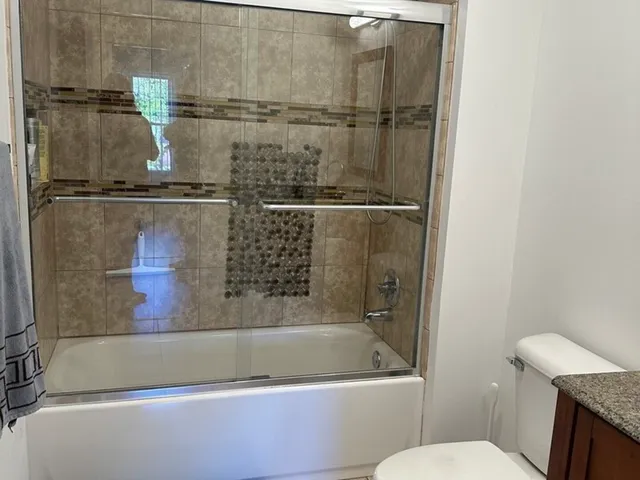 a bathroom with a granite countertop sink vanity mirror and toilet