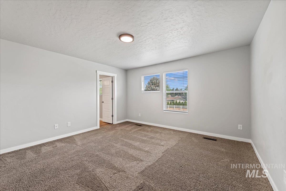 12535 West Victory Road Boise, ID 83709 - Photo 13 of 25 Textured carpet flooring with light gray walls, two windows, and a flush-mount ceiling light