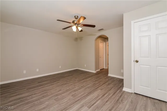 an empty room with wooden floor closet and fan