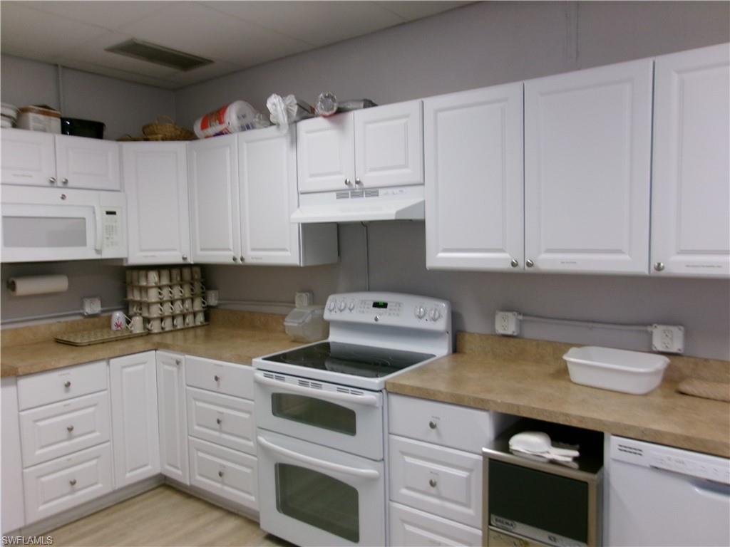 2 Monaco Terrace Naples, FL 34112 - Photo 21 of 24 Kitchen featuring white appliances, light countertops, white cabinetry, and light wood-type flooring