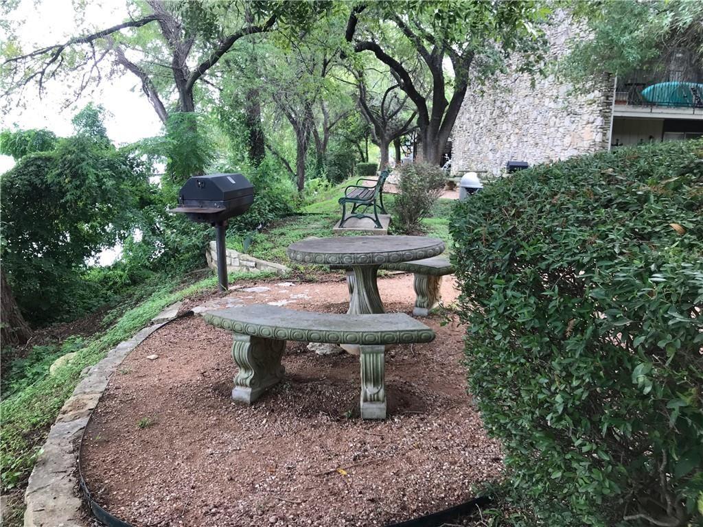 500 East Riverside Drive, Unit 154 Austin, TX 78704 - Photo 14 of 14 Outdoor gathering area featuring a stone-look picnic table with benches, built-in BBQ grill, and mature trees