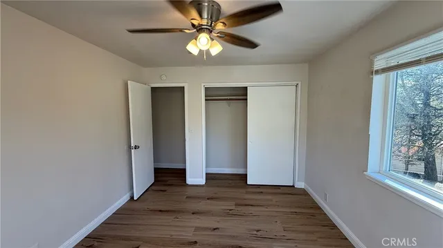 a view of empty room with wooden floor and fan
