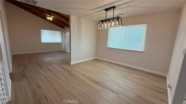 an empty room with wooden floor cabinet and windows